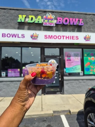 An açaí bowl held up in front of the N Da Bowl storefront sign on Pryor Rd